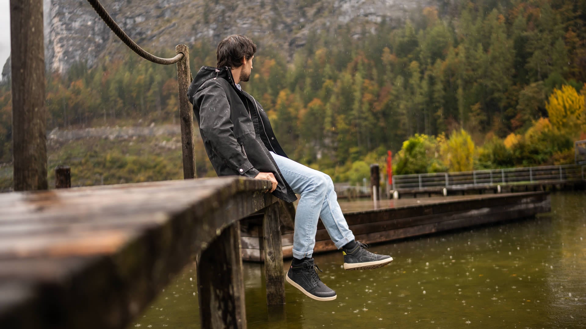 Voděodolné barefoot boty s termoizolací Be Lenka ArcticEdge - Charcoal Black černé s béžovou podrážkou pohled na obutého muže sedícího na lávce nad vodou zprava