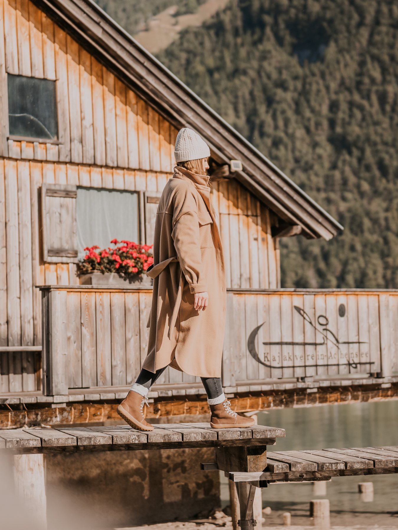 Zimní zateplené vysoké barefoot boty Be Lenka Winter 3.0 - Walnut Brown ořechově hnědé žena jdoucí po mole u vody pohled zprava
