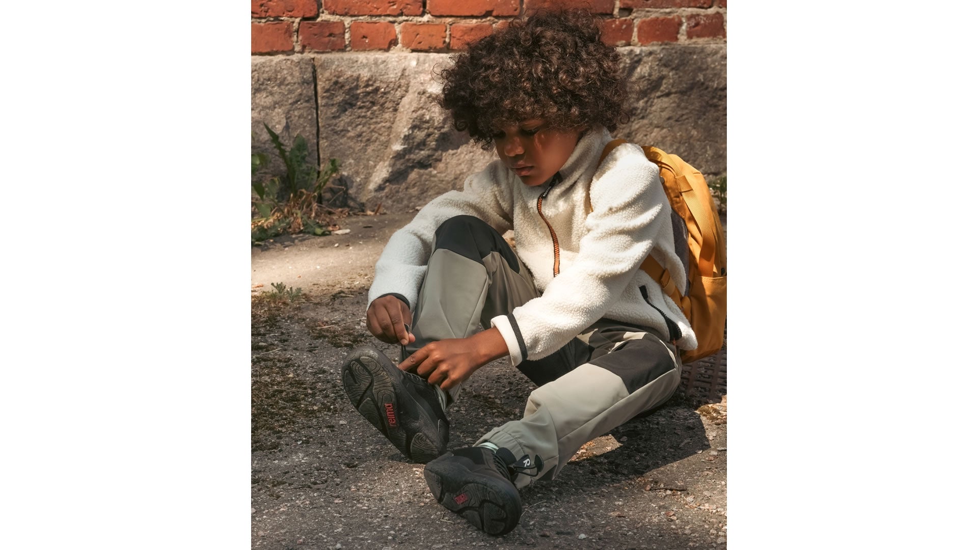 Reima Tallusteli Black - dětské barefoot tenisky s voděodolnou membránou v černé barvě s rychloupínáním - pohled na chlapce zavazující si boty